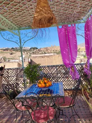 a table with a bowl of fruit on a balcony at Riad Sanaa Rose in Fès