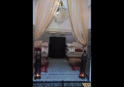 a room with curtains and chairs and a chandelier at Riad Sanaa Rose in Fès