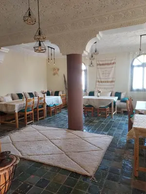 a living room with a table and chairs and a pillar at Riad ma bonne étoile in Kasr Bounou