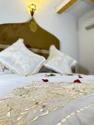a bed with white sheets and pillows with flowers on it at Dar Khmissa Fes-Luxury Stay Fes Medina in Fès