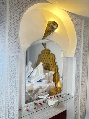 a bedroom with a white bed and a mirror at Dar Khmissa Fes-Luxury Stay Fes Medina in Fès