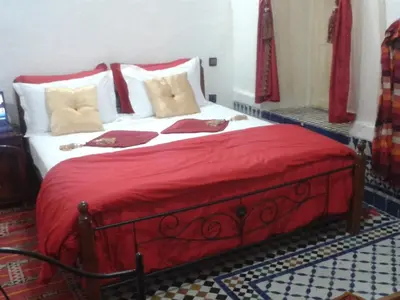 a bedroom with a large bed with red sheets and pillows at Riad Azrou in Azrou