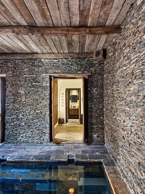 a room with a stone wall and a swimming pool at Villa avec gouvernante et 2 piscines dont une chauffée dans domaine securise in Marrakech