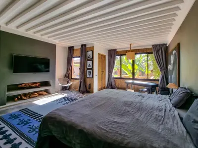 a bedroom with a large bed and a tv at Villa avec gouvernante et 2 piscines dont une chauffée dans domaine securise in Marrakech