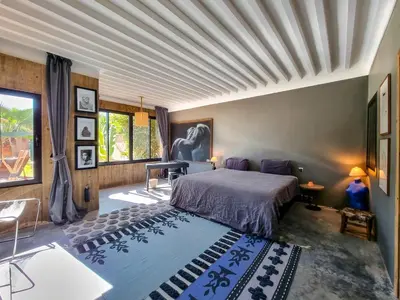 a bedroom with a bed and a table in a room at Villa avec gouvernante et 2 piscines dont une chauffée dans domaine securise in Marrakech