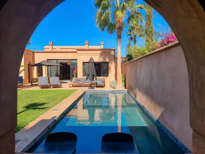 a swimming pool in front of a house at Villa avec gouvernante et 2 piscines dont une chauffée dans domaine securise in Marrakech