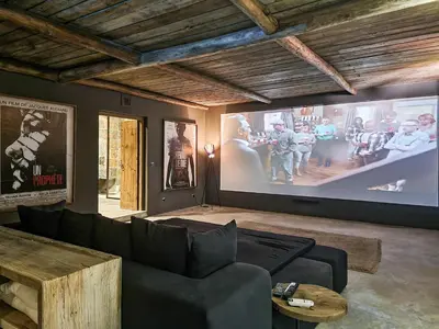 a living room with a couch and a large screen at Villa avec gouvernante et 2 piscines dont une chauffée dans domaine securise in Marrakech