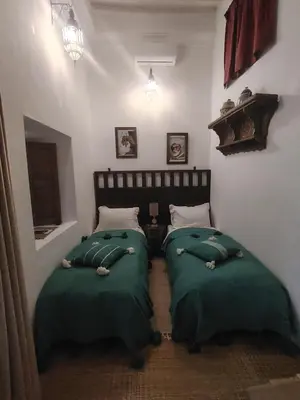 two beds in a room with green covers at La Maison des Amis in Fès