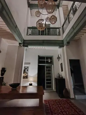 a living room with a wooden table and a door at La Maison des Amis in Fès
