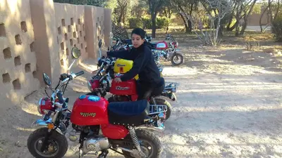 a young boy is sitting on a red motorcycle at ECOLODGE MISS ROSE CHEZ LA FAMILLE in Boumalne