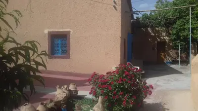 a building with flowers in front of a building at ECOLODGE MISS ROSE CHEZ LA FAMILLE in Boumalne
