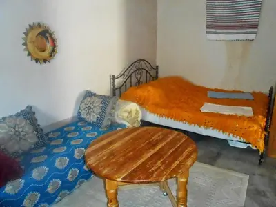 a bedroom with a twin bed and a wooden table at ECOLODGE MISS ROSE CHEZ LA FAMILLE in Boumalne