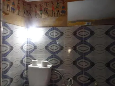 a bathroom with a toilet and blue and white tiles at Maison d'hôtes tilleli in Tamnougalt