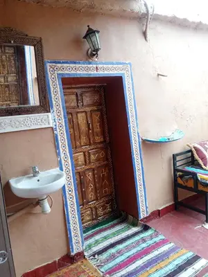 a bathroom with a sink and a wooden door at Maison d'hôtes tilleli in Tamnougalt