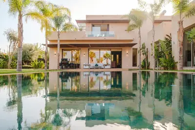 a house with a swimming pool and palm trees at Dar ilyan in Marrakech