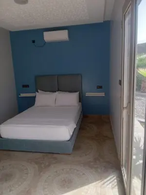 a bed in a room with a blue wall at Ferme Marsa in Guercif