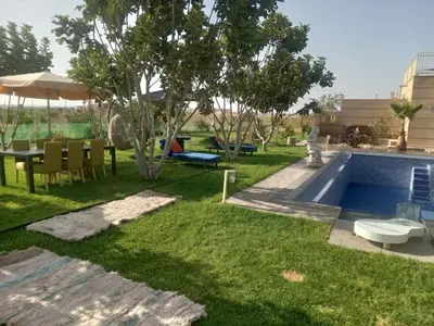 a backyard with a swimming pool with a table and chairs at Ferme Marsa in Guercif