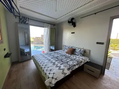 a bedroom with a bed and a view of a pool at Ferme Marsa in Guercif