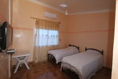 a room with two beds and a desk and a television at Tahla Garden in Tahla