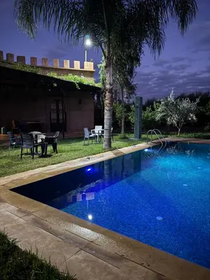 a swimming pool in the yard of a house at night at Motia's farm in Marrakech