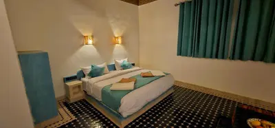 a bedroom with a bed in a room with green curtains at Traditional Riad Merzouga Dunes in Merzouga