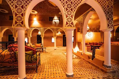 a room with arches and tables in a building at Traditional Riad Merzouga Dunes in Merzouga