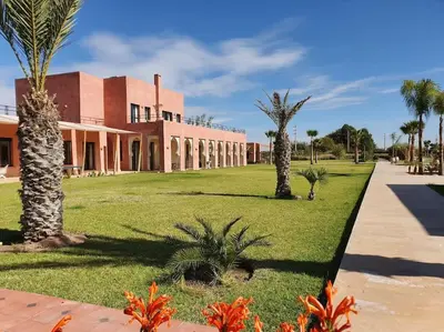 a building with palm trees in front of it at Dar Lalla Mhalla Villa 975m2 5ch - Rt de Fes in Marrakech