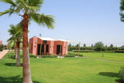 a pink building with palm trees in a park at Dar Lalla Mhalla Villa 975m2 5ch - Rt de Fes in Marrakech