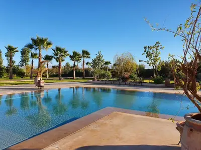 a swimming pool in a park with palm trees at Dar Lalla Mhalla Villa 975m2 5ch - Rt de Fes in Marrakech