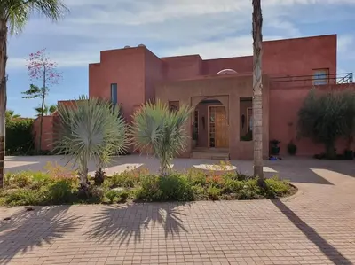 a red building with palm trees in front of it at Dar Lalla Mhalla Villa 975m2 5ch - Rt de Fes in Marrakech