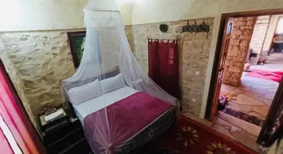 a bedroom with a bed with a mosquito net at Kasbah Dar Talouste in Afela nʼIsly