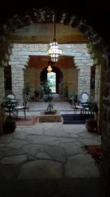 a room with a stone wall with chairs and a chandelier at Kasbah Dar Talouste in Afela nʼIsly