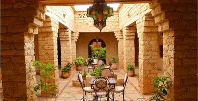 a patio with a table and chairs in a stone building at Kasbah Dar Talouste in Afela nʼIsly