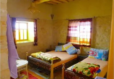 two beds in a room with two windows at Kasbah Dar Talouste in Afela nʼIsly