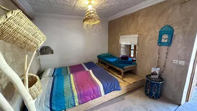 a bedroom with a bed and a table in it at Alliance Berbère - Vallée d'Aït Bouguemez in Timit