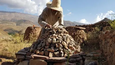 a man making a pile of rocks on a stack of rocks at Alliance Berbère - Vallée d'Aït Bouguemez in Timit