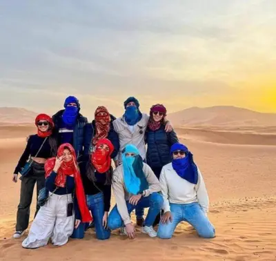 a group of people posing for a picture in the desert at Holiday Desert Camp in Merzouga