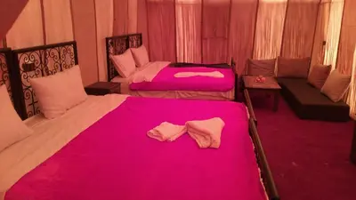 two beds in a room with pink sheets at Holiday Desert Camp in Merzouga