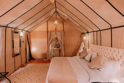 a bedroom with a bed in a tent at Merzouga starlit desert camp in Hassilabied