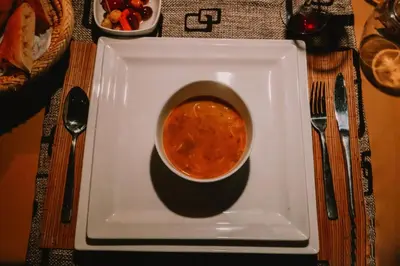 a bowl of soup on a plate on a table at Merzouga starlit desert camp in Hassilabied