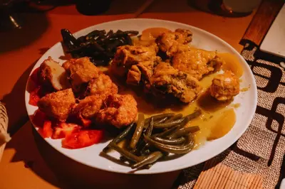 a plate of food with chicken and vegetables on a table at Merzouga starlit desert camp in Hassilabied