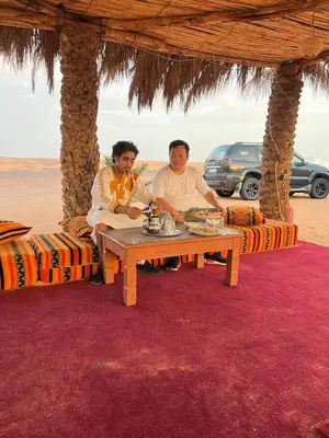 two men sitting at a table in the desert at Merzouga starlit desert camp in Hassilabied