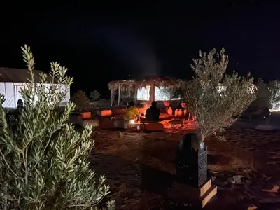 a group of people sitting under a gazebo at night at Merzouga starlit desert camp in Hassilabied