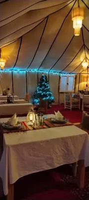 a table with a christmas tree in a tent at Merzouga starlit desert camp in Hassilabied