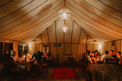 a group of people sitting at tables in a tent at Merzouga starlit desert camp in Hassilabied