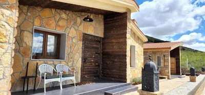 a stone house with two white chairs and a window at Chalets-Appartements Tourtite in Ifrane