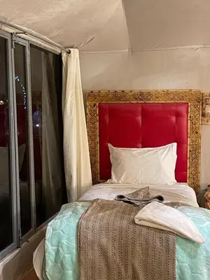 a bed with a red headboard in a room at Merzouga Luxury Dunes Camp in Merzouga