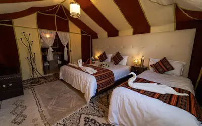 a bedroom with three beds with swans on them at Merzouga Luxury Dunes Camp in Merzouga