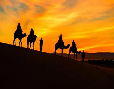 a group of people riding horses in the desert at sunset at Merzouga Luxury Dunes Camp in Merzouga