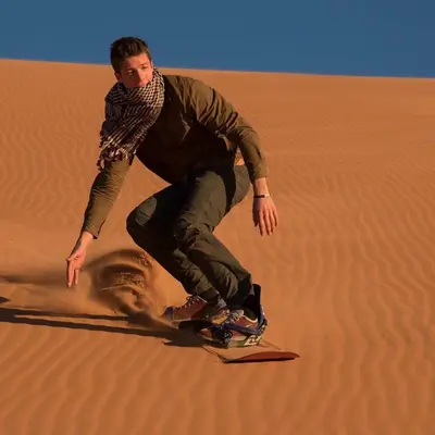 a man on a snowboard in the desert at Diament Luxury Camp-Sahara Desert Experience in Merzouga in Merzouga